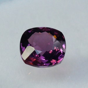 Pu&ograve; includere: Una pietra preziosa di colore viola scuro con taglio a cuscino. La pietra preziosa &egrave; sfaccettata e ha un'alta lucentezza.