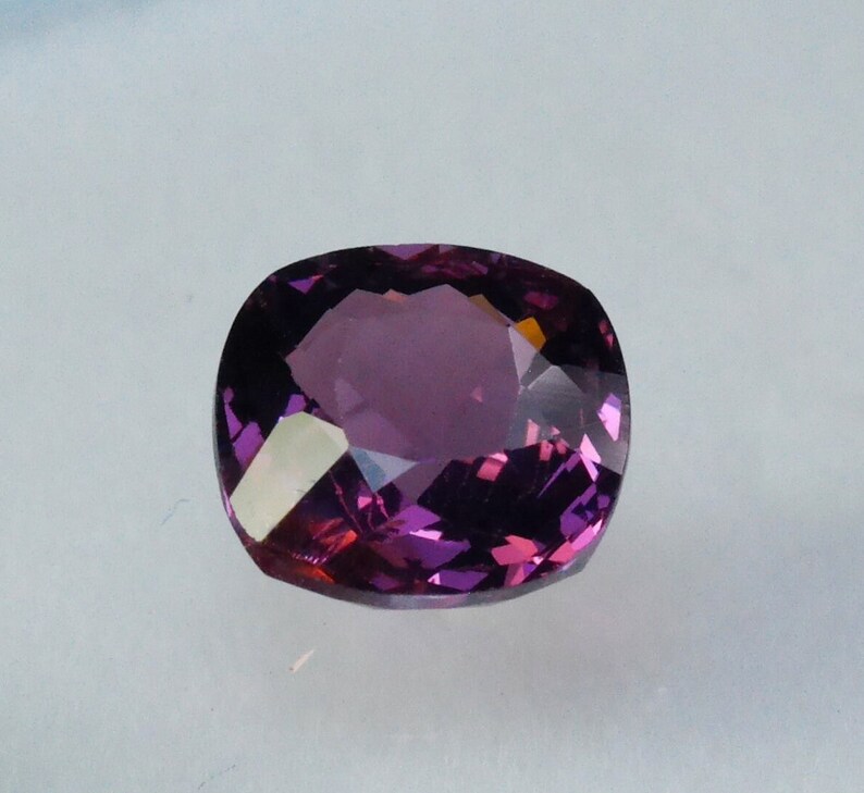 Pu&ograve; includere: Una pietra preziosa di colore viola scuro con taglio a cuscino. La pietra preziosa &egrave; sfaccettata e ha un'alta lucentezza.