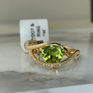 May include: A gold ring with a green gemstone and a row of small diamonds. The ring has a twisted band design.
