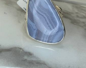 May include: A silver ring with a light blue agate stone. The stone has a swirling pattern of white and light blue.