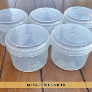 May include: Five clear, round plastic containers with lids are arranged on a wooden surface. The containers are empty and appear to be new. The text "ALL PROFITS DONATED" is at the bottom of the image.