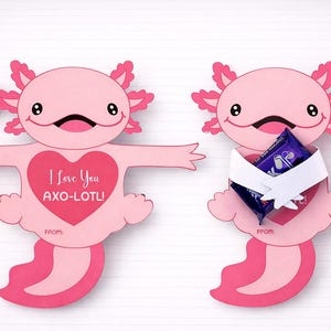 May include: Two pink axolotl-shaped Valentine's Day cards with red heart accents. One card has outstretched arms and a heart with "I Love You AXO-LOTL!" text. The other holds a candy bar.