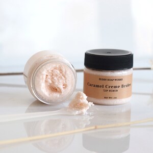 Może przedstawiać: Mały słoiczek r&oacute;żowego peelingu do ust z etykietą "Sudsy Soap Works Caramel Creme Brulee Lip Scrub Net Wt 1 oz".