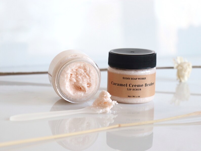 Może przedstawiać: Mały słoiczek r&oacute;żowego peelingu do ust z etykietą "Sudsy Soap Works Caramel Creme Brulee Lip Scrub Net Wt 1 oz".