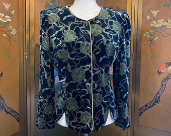 May include: A black velvet jacket with a green floral pattern and gold trim. The jacket has a button-up front and long sleeves.