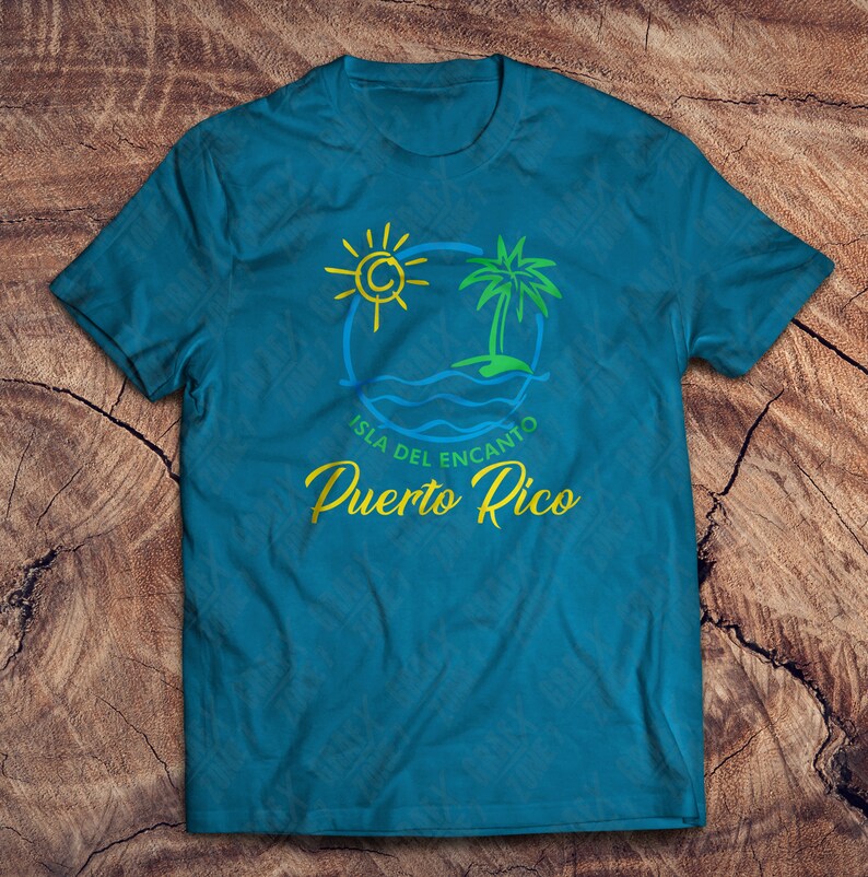 May include: A teal blue t-shirt with a graphic design of a palm tree, sun, and waves. The text "Isla del Encanto Puerto Rico" is printed in yellow and green.