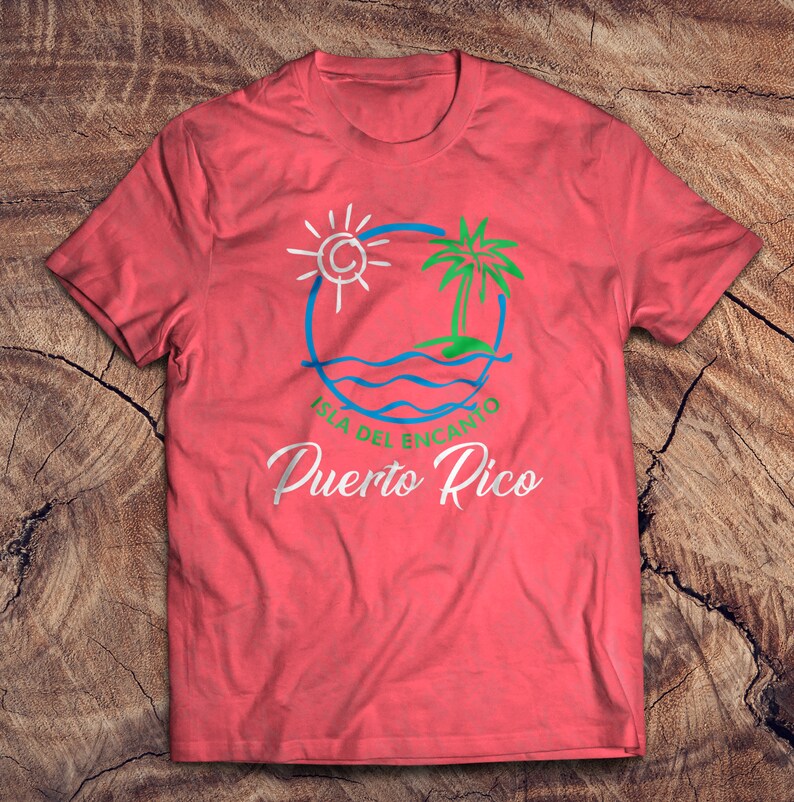 May include: A red t-shirt with a white graphic design of a sun, palm tree, and waves in a circle. The text "Isla del Encanto Puerto Rico" is written below the graphic.