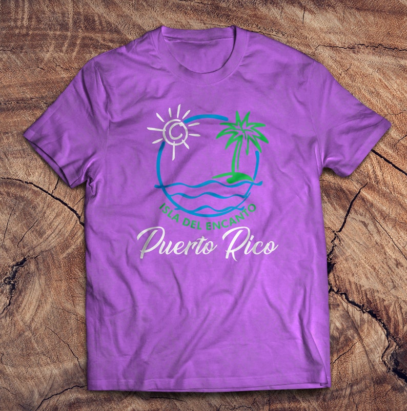 May include: Purple t-shirt with a white graphic of a sun, palm tree, and waves in a circle. The text "Isla del Encanto Puerto Rico" is below the graphic.