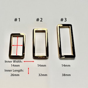 Peut inclure: Trois anneaux métalliques rectangulaires dorés de différentes tailles. Le plus petit anneau a des dimensions intérieures de 14 mm de large et 26 mm de long. Les deux autres anneaux mesurent 14 mm de large et 32 mm et 38 mm de long. Le texte "#1", "#2" et "#3" est inclus.