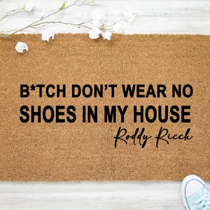 May include: A brown coir doormat with the text "B*tch don't wear no shoes in my house" and the signature "Roddy Ricch" in black lettering.
