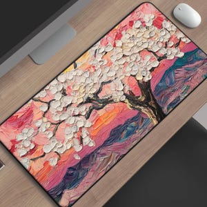 May include: Rectangular mousepad featuring a vibrant, impressionistic painting of a blossoming tree. The artwork showcases a palette of pink, white, orange, and blue hues, creating a textured, artistic design. The mousepad is placed on a wooden desk.