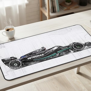 May include: A rectangular desk mat featuring a detailed technical sketch of a black and teal Mercedes-AMG Petronas Formula One race car. The design is set against a white grid background with faint handwritten notes and engineering lines.