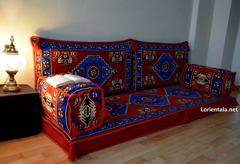 Puede incluir: Un coj&iacute;n de suelo rojo y azul con un coj&iacute;n de respaldo a juego y una almohada m&aacute;s peque&ntilde;a. Los cojines est&aacute;n dispuestos en una configuraci&oacute;n similar a un sof&aacute;.