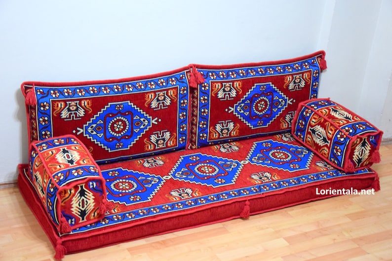 Puede incluir: Un coj&iacute;n de suelo rojo, azul y blanco con un coj&iacute;n de respaldo a juego y dos cojines m&aacute;s peque&ntilde;os. Los cojines est&aacute;n dispuestos en un estilo tradicional marroqu&iacute;.