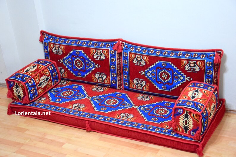 Puede incluir: Un coj&iacute;n de suelo rojo, azul y blanco con estampado con cuatro almohadas a juego. El coj&iacute;n est&aacute; hecho de una tela suave y mullida y tiene un dise&ntilde;o tradicional.