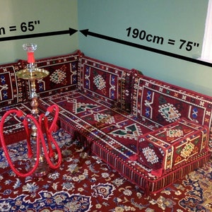 May include: A red and gold traditional Moroccan floor seating set with a patterned design. The set includes a large sofa, two smaller cushions, and a small square cushion. The sofa measures 65 inches long and 75 inches wide.