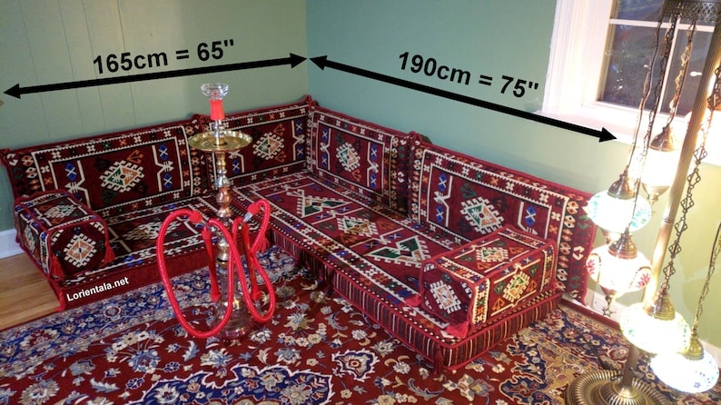 May include: A red and gold traditional Moroccan floor seating set with a patterned design. The set includes a large sofa, two smaller cushions, and a small square cushion. The sofa measures 65 inches long and 75 inches wide.