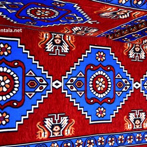Puede incluir: Una alfombra roja, azul y blanca con un dise&ntilde;o geom&eacute;trico. La alfombra tiene un patr&oacute;n repetitivo de cuadrados y c&iacute;rculos.