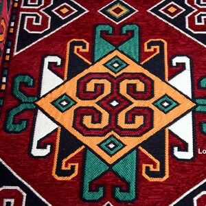 May include: A close-up of a red, black, white, green, and orange patterned rug with a geometric design. The rug has a traditional, ornate look.