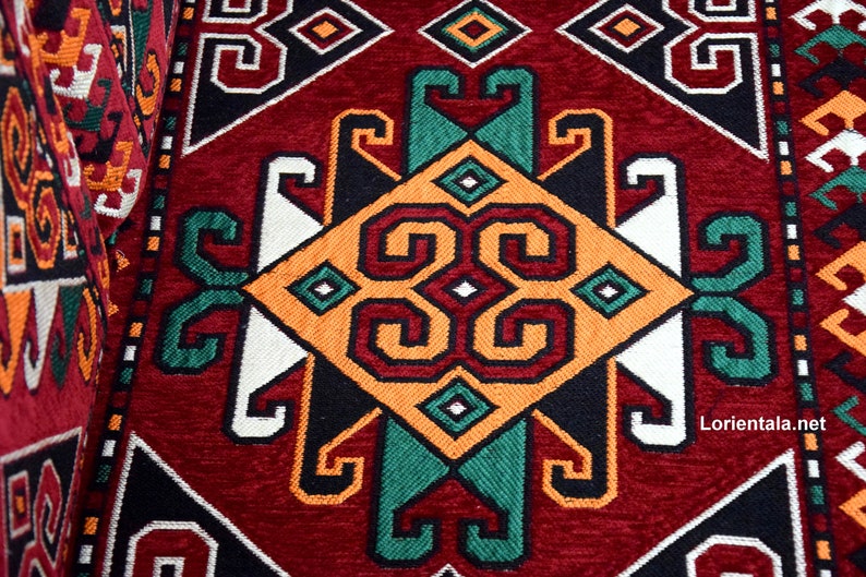 May include: A close-up of a red, black, white, green, and orange patterned rug with a geometric design. The rug has a traditional, ornate look.