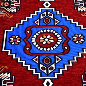 Puede incluir: Una alfombra roja con un patr&oacute;n geom&eacute;trico azul y blanco en el centro. El patr&oacute;n presenta un cuadrado grande con un cuadrado m&aacute;s peque&ntilde;o en el interior, rodeado por un borde blanco y azul.