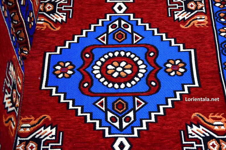 Puede incluir: Una alfombra roja con un patr&oacute;n geom&eacute;trico azul y blanco en el centro. El patr&oacute;n presenta un cuadrado grande con un cuadrado m&aacute;s peque&ntilde;o en el interior, rodeado por un borde blanco y azul.