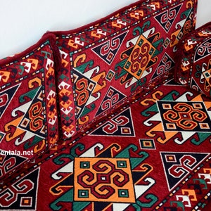 May include: A red, green, white, and orange patterned floor cushion with two matching pillows. The cushion and pillows feature a geometric design.