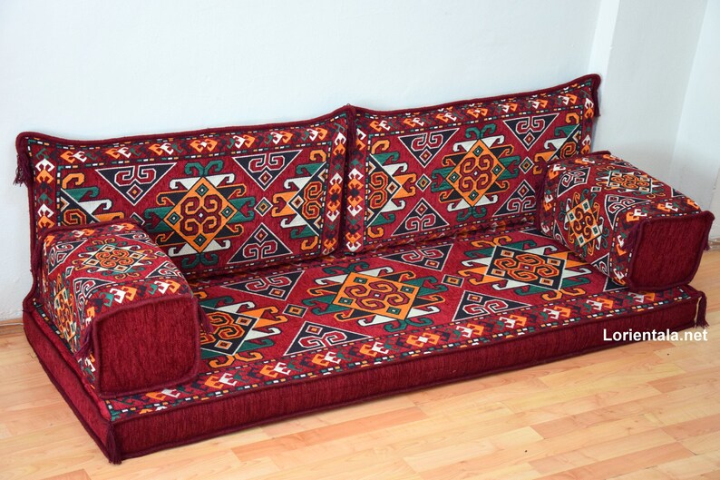 May include: A red, green, and yellow patterned floor cushion with a matching back cushion and two smaller cushions. The cushions are arranged in a traditional seating configuration.
