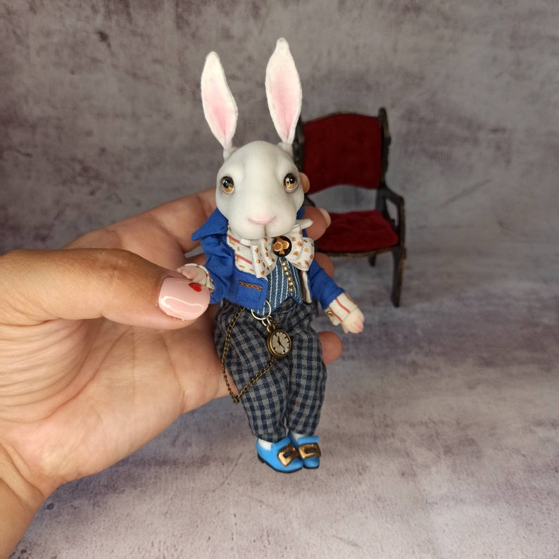 white rabbit in a blue jacket with a clock from Alice in Wonderland The author's doll .br white rabbit in a blue jacket with a clock from Alice in Wonderland The author's doll .br
