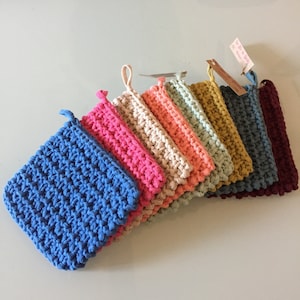 Peut inclure: Un ensemble de huit maniques en crochet de différentes couleurs, notamment bleu, rose, beige et vert. Les maniques sont faites d'un fil doux et texturé et ont une forme carrée.