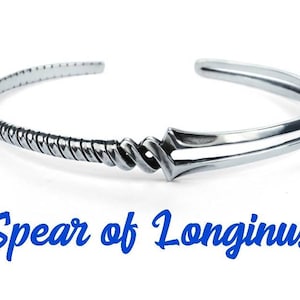 Może przedstawiać: Srebrna bransoletka z wzorem splecionej liny i zapięciem w kształcie grotu wł&oacute;czni. Bransoletka jest wygrawerowana słowami "Spear of Longinus".