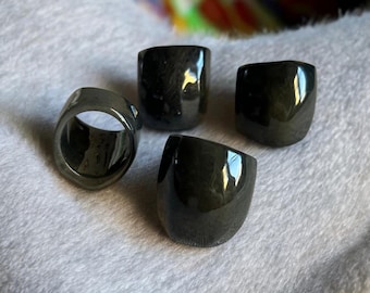 May include: Four black, shiny, ring-shaped objects with a rounded, rectangular design. The rings are made of a smooth, glossy material.