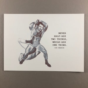 May include: A black and white print featuring a vintage illustration of two wrestlers in action. The print includes the quote, "NEVER HALF-ASS TWO THINGS, WHOLE-ASS ONE THING. -RON SWANSON-" in a bold, sans-serif font. The background is plain white.
