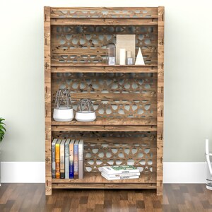 Puede incluir: Una estanter&iacute;a de madera con tres estantes y un patr&oacute;n geom&eacute;trico en la parte delantera. Los estantes est&aacute;n llenos de libros, objetos decorativos y plantas.