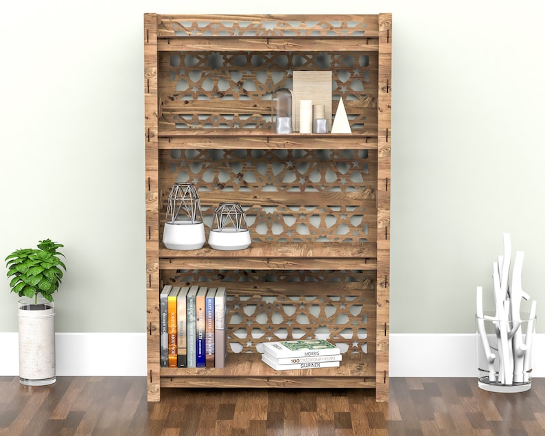 Puede incluir: Una estanter&iacute;a de madera con tres estantes y un patr&oacute;n geom&eacute;trico en la parte delantera. Los estantes est&aacute;n llenos de libros, objetos decorativos y plantas.