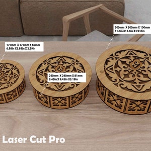 Può includere: Tre scatole di legno con intricati disegni tagliati al laser. Le scatole hanno un diametro di 15 cm, 24 cm e 30 cm. Le scatole sono realizzate in legno naturale e hanno un colore marrone chiaro.