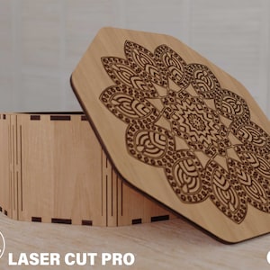 Pode incluir: Uma caixa de madeira de cor clara com uma tampa decorativa. A tampa apresenta um intrincado design floral cortado a laser. A caixa está aberta, revelando o seu interior. O texto "LASER CUT PRO" é visível na parte inferior da imagem.