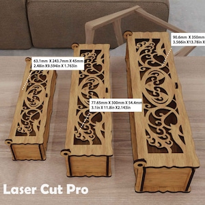 May include: Three wooden boxes with intricate laser cut designs. The boxes are different sizes, with measurements in inches and millimeters. The largest box is 13.78 inches by 2.48 inches by 3.57 inches. The boxes are made of light brown wood and have a natural finish.