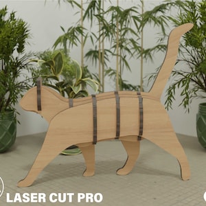 May include: A wooden cat sculpture in light brown with dark brown detailing. The cat is depicted walking, with its tail up. The sculpture has a layered design and the text "Laser Cut Pro" is visible.