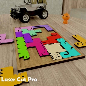 Op de afbeelding: Een houten puzzel met kleurrijke dierenvormen, waaronder een roze varken, een groene slang, een blauwe vis, een gele eend en een rode kat. De puzzelstukken zijn gerangschikt op een houten basis met de woorden "Laser Cut Pro" erop gedrukt.