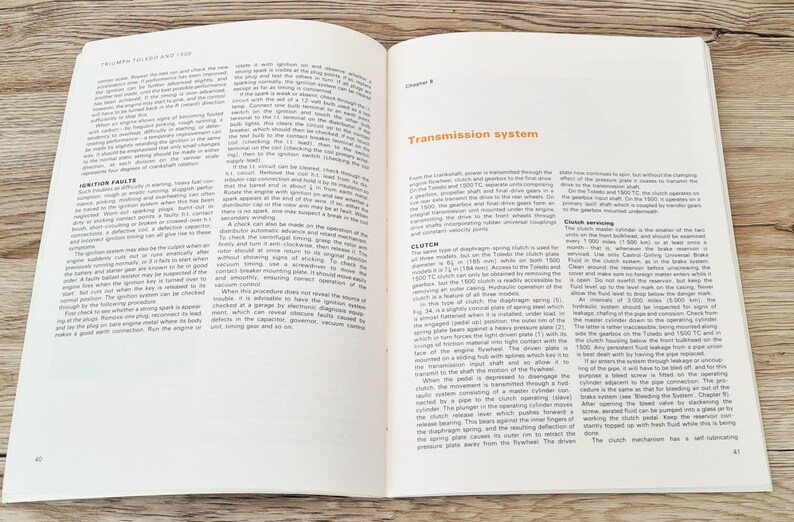 May include: A close-up of two pages from a vintage car repair manual. The pages are open to Chapter 8, Transmission System. The text discusses the clutch and clutch servicing. The pages are printed on white paper with black text.