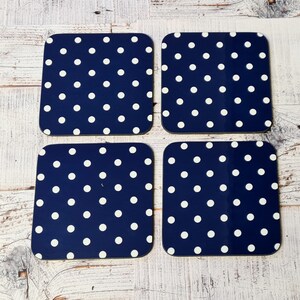 May include: Set of four blue and white polka dot coasters. The coasters are square and have a dark blue background with white polka dots.