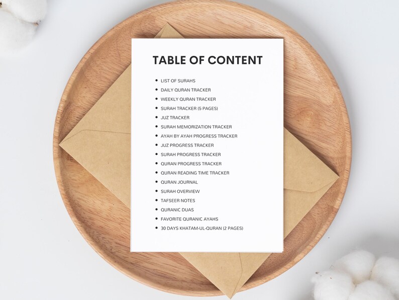 May include: A white sheet of paper with a black heading "TABLE OF CONTENT" and a list of items related to Quran study, including "List of Surahs", "Daily Quran Tracker", "Weekly Quran Tracker", "Surah Tracker (5 pages)", "Juz Tracker", "Surah Memorization Tracker", "Ayah by Ayah Progress Tracker", "Juz Progress Tracker", "Surah Progress Tracker", "Quran Progress Tracker", "Quran Reading Time Tracker", "Quran Journal", "Surah Overview", "Tafseer Notes", "Quranic Duas", "Favorite Quranic Ayahs", and "30 Days Khatam-ul-Quran (2 pages)".