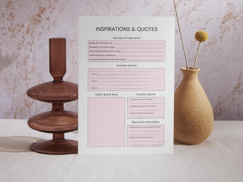 May include: A white paper titled "INSPIRATIONS & QUOTES" with pink boxes for notes. A brown glass candle holder and a beige vase with dried flowers are on either side of the paper.