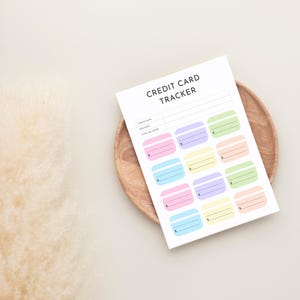 May include: A white sheet of paper with the words "CREDIT CARD TRACKER" printed at the top. The paper has spaces for tracking credit card information and colorful credit card-shaped boxes.