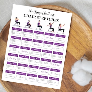 May include: A white printed sheet with a 30-Days Challenge Chair Stretches program. The sheet has a grid of purple boxes with exercise instructions and illustrations of people doing chair stretches. The sheet is on a wooden tray.