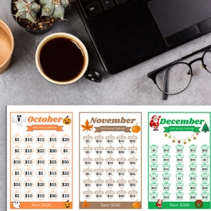 May include: Three printable charts for a $300 savings challenge. The charts are themed for October, November, and December with Halloween, Thanksgiving, and Christmas icons. Each chart has a grid of 25 squares with dollar amounts to save each day.