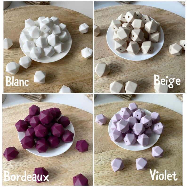 May include: Four sets of silicone teething beads in different colors: white, beige, burgundy, and lavender. Each set is displayed on a white plate on a wooden surface. The colors are labeled "Blanc", "Beige", "Bordeaux", and "Violet".