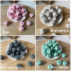 May include: Four sets of silicone teething beads in different colors: rose, brown marble, gray anthracite, and green mint. Each set is displayed on a white plate and a wooden surface. The beads are shaped like irregular pentagons with a hole in the center.