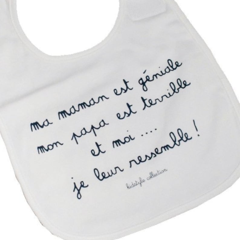 May include: White baby bib with black text that reads "ma maman est g&eacute;niale mon papa est terrible et moi.... je leur ressemble!" and "kidstyle collection".